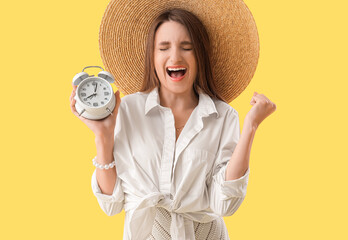 Canvas Print - Young woman with alarm clock shouting on yellow background