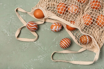 Wall Mural - String bag with painted Easter eggs on grey background