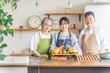 野菜を持つ高齢者夫婦と若い日本人（栄養士・家事代行・介護）
