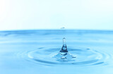 Fototapeta Łazienka - Splash of clear water with drop on light blue background, closeup