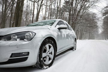 Wall Mural - Car with winter tires on snowy road in forest, space for text