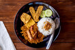 Nasi Uduk Betawi, or Nasi Lemak, coconut flavored steamed rice dish from Betawi, Jakarta. Topped with several dishes, tahu tofu, soybean, tempe, tempeh, fried chicken, and served on plate. top view