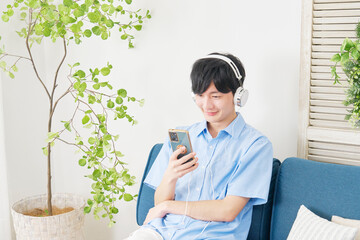 Poster - リビングでスマートフォンで音楽を聴く男性