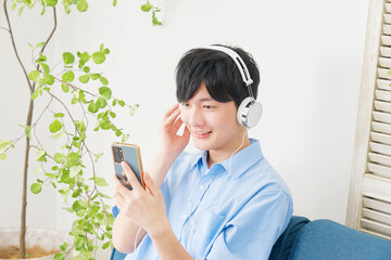 Poster - リビングでスマートフォンで音楽を聴く男性