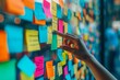 This close-up image features a hand pointing at vibrant sticky notes on a board, epitomizing the collaborative spirit and inventive brainstorming integral to project planning.