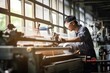 Asian man turner in glasses and overall works in production on machine against background of windows