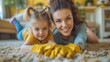© Jammy Jean - Mom and her daughter cleaning carpet spots inside their house. Wearing yellow gloves.