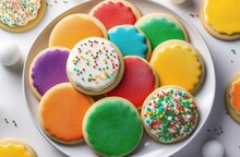 A Plate Of Homemade Sugar Cookies Decorated With Frosting. Round Shaped Cookies. Glaze Of Bright Colors. Sprinkled Sugar Balls Of Different Colors On Top. Banner With Space For Text. Light Gray Concre