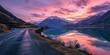 A highway curving around a peaceful lake surrounded by mountains, reflecting the colors of the sunrise