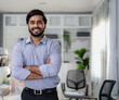 © Nassorn - Friendly Indian businessman standing arms crossed in modern office smiling. Confident young smart bearded man entrepreneur looking at camera smiling. Successful India ethnic manager work in workplace.