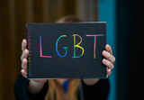 Fototapeta Tęcza - Kobieta trzyma kartkę z kolorowym napisem LGBT