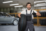 Fototapeta Panele - Car mechanic is holding tire in hand and is ready for changing tires.