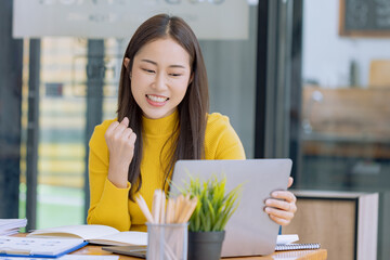 Happy asian young businesswoman excited with laptop at workplace.