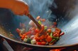 hand tossing vegetables in a professional wok