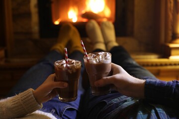 Sticker - Couple with glasses of hot cocoa near fireplace at home, closeup