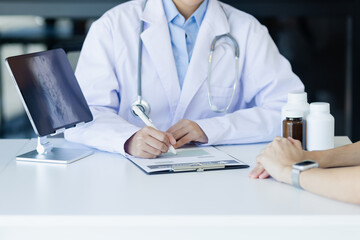 Wall Mural - Asian female doctor explain to patient and looking at xrays indoors office, healthcare and medical concept.