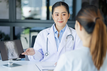 Wall Mural - Asian female doctor explain to patient and looking at xrays indoors office, healthcare and medical concept.