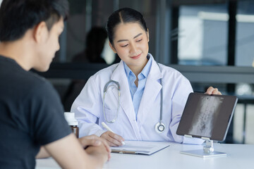 Wall Mural - Asian female doctor explain to patient and looking at xrays indoors office, healthcare and medical concept.