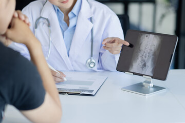 Wall Mural - Asian female doctor explain to patient and looking at xrays indoors office, healthcare and medical concept.