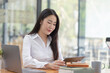 © SOMKID - Happy asian young businesswoman using digital tablet  sitting in office working space.