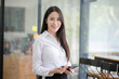 © SOMKID - Happy asian young businesswoman using digital tablet standing in office office working space.