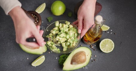 Wall Mural - Woman mixing Sliced chopped avocado fruit with lime juice and species in a glass bowl at domestic kitchen