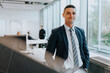 © Maskot - Portrait of confident young businessman standing at corporate office