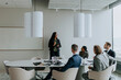 © Maskot - Businesswoman discussing strategy with colleagues in board room during meeting