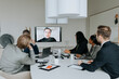 © Maskot - Multiracial colleagues discussing strategy through video conference in board room