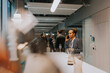 © Maskot - Smiling mature businesswoman talking on mobile phone while standing by table in conference