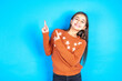 © Roquillo - beautiful kid girl wearing orange sweater points at copy space indicates for advertising gives right direction