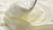 Sour Cream Or Greek Yogurt Scooping  With A Spoon, Swirl, Rotating Texture, White Cream Background, Close Up. Dairy Product. Delicious Organic Creamy Yogurt. Tasty Milk Cream Macro Shot