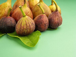 Wall Mural - Top view of figs fruit with fresh leaves on a green background.