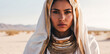 beautiful young girl with white cowl and golden ethnic jewelries looks intently at the camera. Woman in the hood and clothes for the desert, close up fantasy beauty portrait