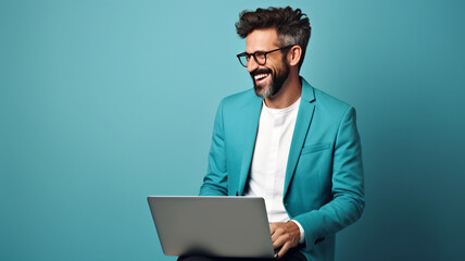 man sitting and smiling with laptop on blue background