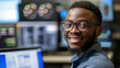 Black male cybersecurity analyst smiling at camera, with security monitors in the background. Generative AI.