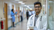 Smiling Indian male doctor in a white coat holding a tablet in the hospital corridor. Generative AI.