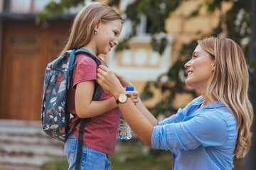 Happy family preparing for school. Little girl with mother. Mother saying goodbye to her daughter at school. Beginning of lessons. First day of fall.