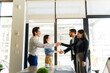 Profile view of two business partners greeting some clients and shaking hands during an office visit