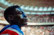 © ADDICTIVE STOCK - AI Generated Image African European man with makeup in the color of the French flag watching the sports event in stadium