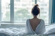 Patient woman sitting on bed in hospital hopeful for better days looking out the window