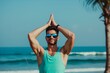fitness enthusiast in sunglasses doing yoga on the beach