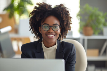 Wall Mural - Happy smiling African American business woman in suit and glasses looking at monitor screen camera having online webinar or video call or conference with colleague sitting in office. 