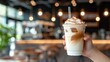 Cafe customer holding iced coffee drink with straw on blurred background, copy space for text