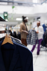 Wall Mural - Male shirts hanging on rack for sale in retail shopping mall with blurred background. Casual trendy menswear apparel on hangers in fashion boutique close up selective focus