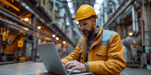 A focused engineer in an industrial facility uses a laptop, ensuring safety and control.