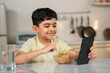 © WESTOCK - Indian preteen kid eating noodles while using mobile phone at home on dining table - concept of unhealthy lifestyle, internet addiction and technology