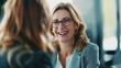 © Patrick - Happy mature professional business woman executive hr manager having job interview or business discussion with female applicant or colleague sitting at workplace in corporate office meeting.