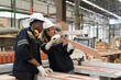 © amorn - Male and female carpenter inspecting quality of processed wood in lumber storage factory. Warehouse and factory SME, Startup and small business concept