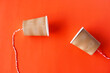 DIY paper cups with string on red background. Concept, telephone toy. Concept, telephone toys which apply with science knowledge about vibration sound through straining strings causing us to hear.   